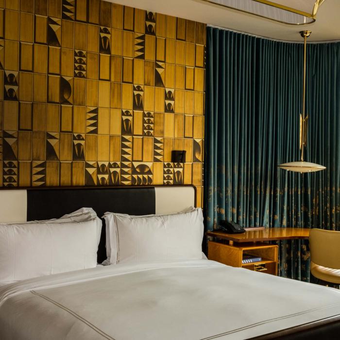 Hotel room at Viceroy Chicago with a large bed and an accent wall made of textured gold panels