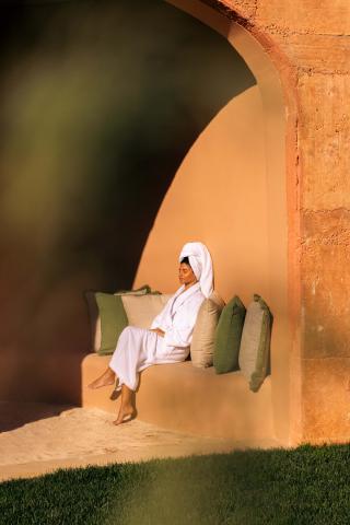 A woman sits in the sun outside of a spa