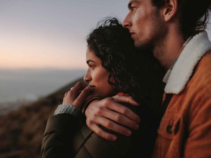 a couple hugging while watching the sunset