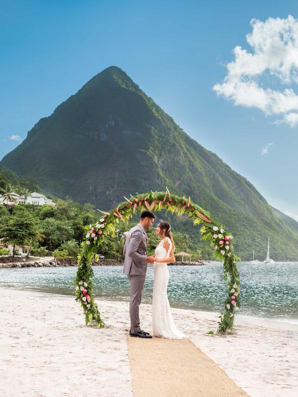 A couple getting married on the beach at Sugar Beach with themountains behind them