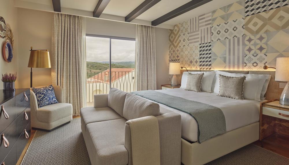 Bedroom with sofa at the foot of the bed and a small chair