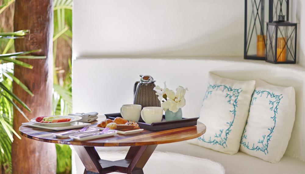 A small round table with coffee and breakfast food items at Viceroy Riviera Maya