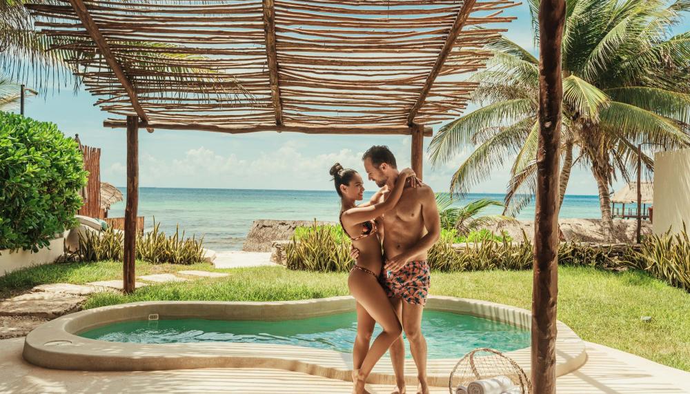 A couple in swimwear holding each other by their private pool at Viceroy Riviera Maya
