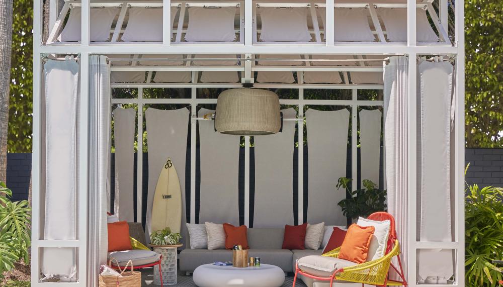 A cabana with a long couch and lounger chairs near the pool at Viceroy Santa Monica