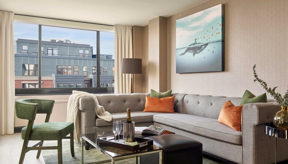 A room at Viceroy Washington DC with an L-shape couch, coffee table, chair, and balcony