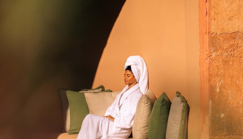 A woman sits in the sun outside of a spa