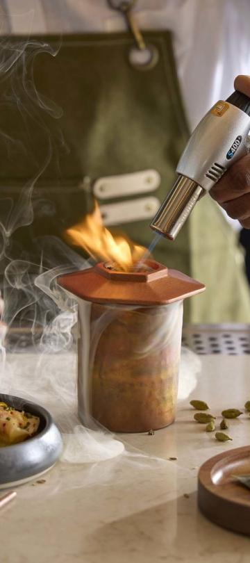 A bartender at Pandan applies flames to prepare a palisade cocktail