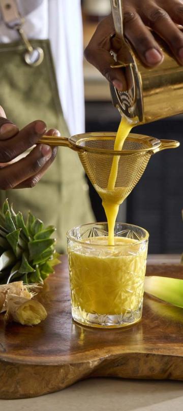 A bartender at Pandan strains a fruit juice to make a Red Panda cocktail
