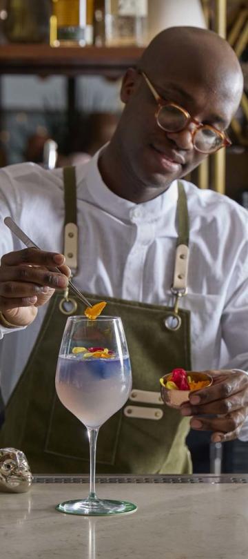 A bartender at Pandan pours a cocktail with yuzu
