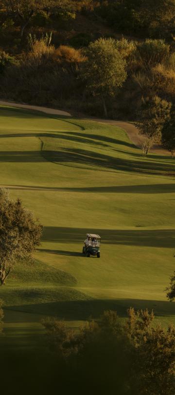 People riding a golf buggy on a green at Viceroy Ombria Algarve