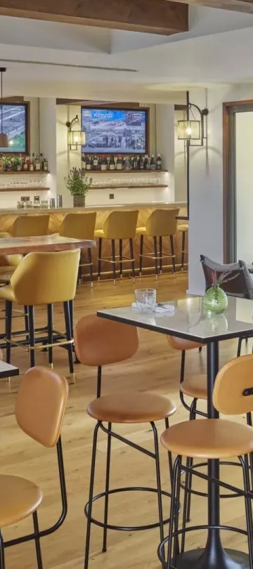 The Casa e Fora dining room at Ombria Algarve, with high four-top tables and a long bar section