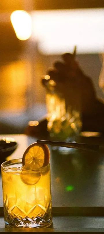Patrons at Salpico Pool Bar enjoy a bright orange drink with an orange garnish, at dusk