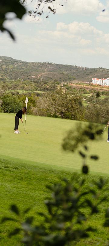 Two players on the green at Ombria golf course, with Viceroy Ombria Algarve in the background