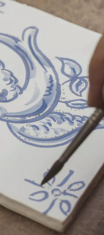 A person painting a blue bird in a greek tile style at Ombria Algarve