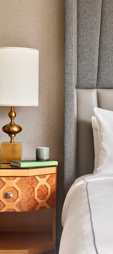 close up of lamp, book and candle on side table beside bed
