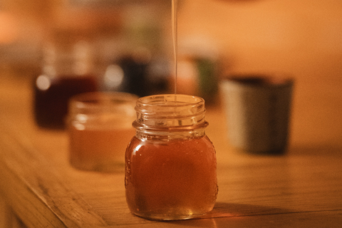 Honey being drizzled into a glass jar
