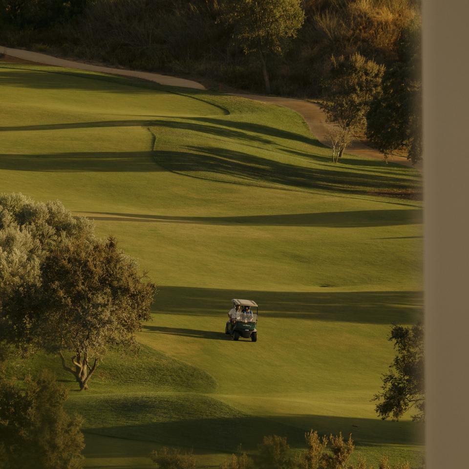 People riding a golf buggy on a green at Viceroy Ombria Algarve