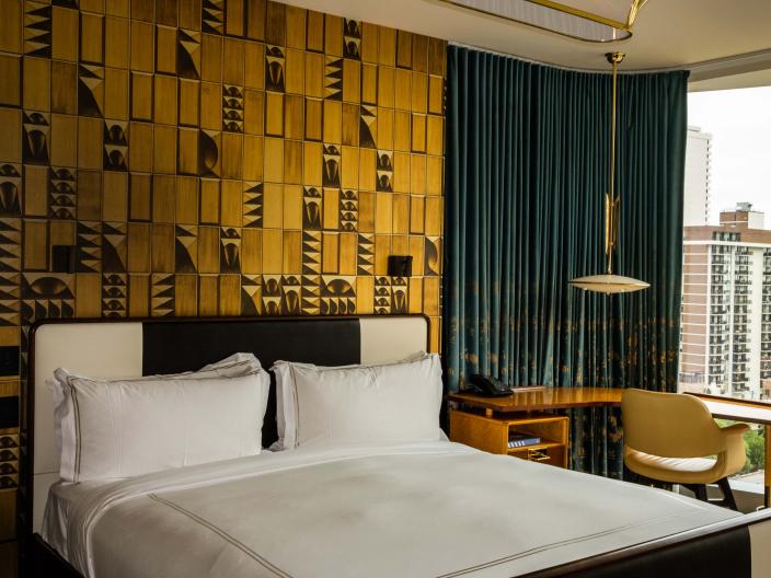 Hotel room at Viceroy Chicago with a large bed and an accent wall made of textured gold panels