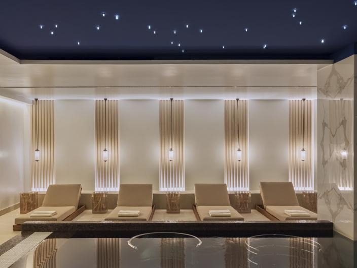 A row of reclining chairs in front of a reflecting pool at the Viceroy Kopaonik Serbia spa
