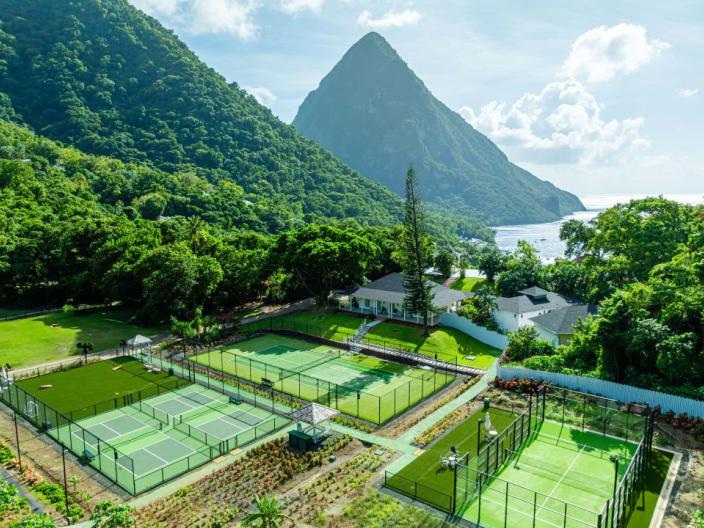 Grass tennis courts nestled amongst tropical trees at the base of the Pitons at Sugar Beach