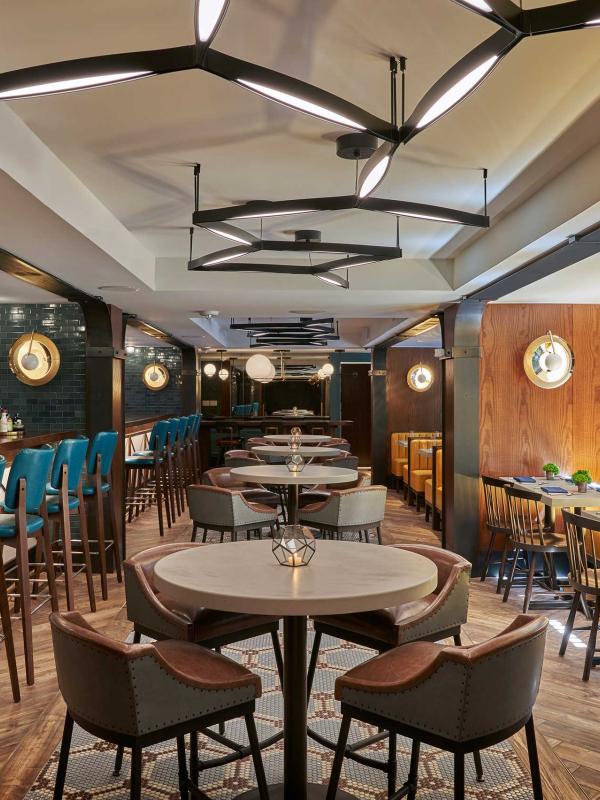 The dining room of Dovetail restaurant at Viceroy Washington DC, with yellow booths and bar seating