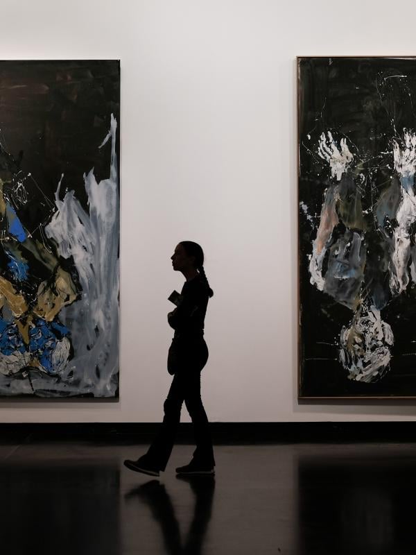 A woman walking between two large paintings in the national museum in Washington