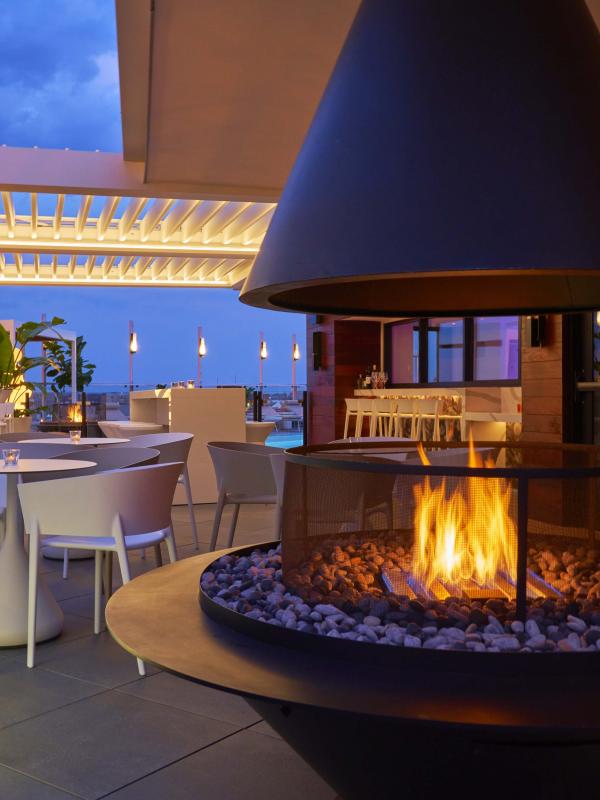 A restaurants patio with a large fire pit and lounge area at Viceroy Zena
