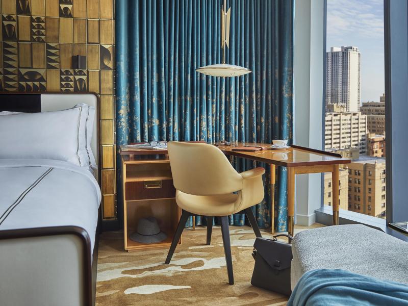 A boomerang desk in a Viceroy hotel room, next to a window looking out on the Chicago skyline
