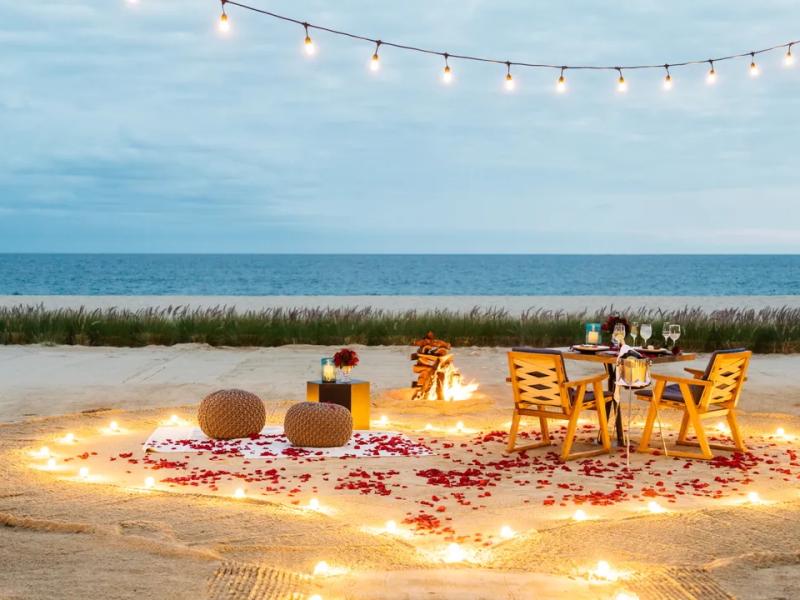 A candle lit walk way on the beach to a private table for the private beach dining event