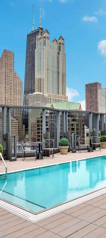An outdoor rooftop pool at Viceroy Chicago, with high-rise architecture in the background